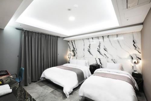two beds in a room with a large window at El Tower Hotel in Gunsan