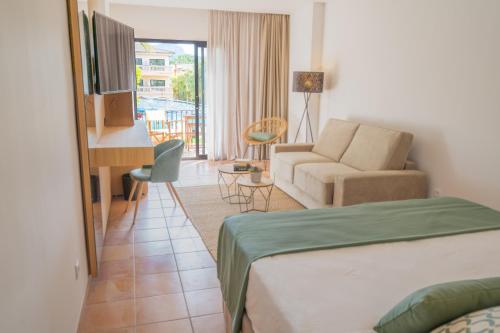 a hotel room with a bed and a couch and a desk at Mon Port Hotel & Spa in Port d’Andratx