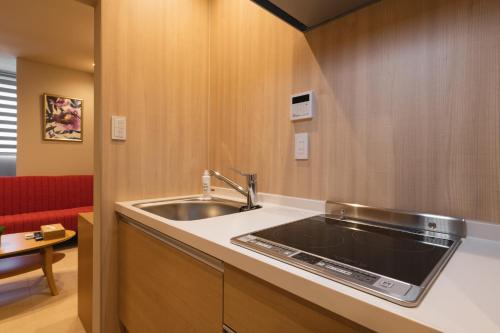 a kitchen with a sink and a red couch at GRAND BASE Crane in Fukuoka