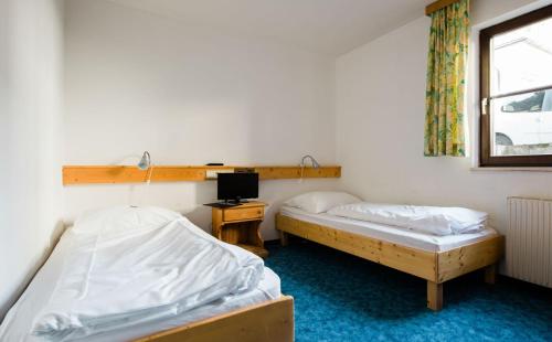 two beds in a room with a desk and a tv at Heart Hotel Sylvia in Ischgl