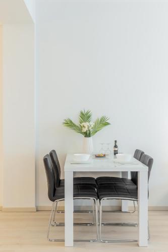 a white table with black chairs and a vase of flowers at ATLAS UNIRII: Upscale Flats in the Heart of Bucharest! in Bucharest