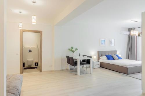 a white bedroom with a bed and a table at ATLAS UNIRII: Upscale Flats in the Heart of Bucharest! in Bucharest