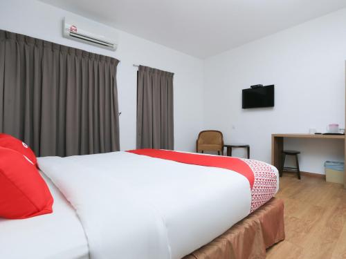 1 dormitorio con cama blanca y almohadas rojas en OYO 89915 East Mount Hotel en Kukup