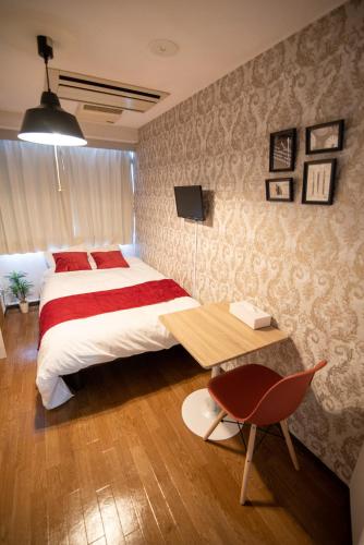 a bedroom with a large bed and a desk and a chair at Vail sta Takenotsuka in Tokyo