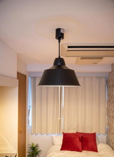 a black light hanging over a bed with red pillows at Vail sta Takenotsuka in Tokyo