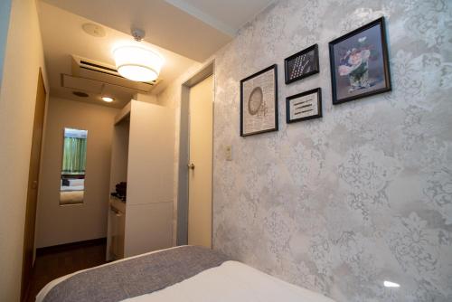 a bedroom with a bed and a wall with pictures at Vail sta Takenotsuka in Tokyo