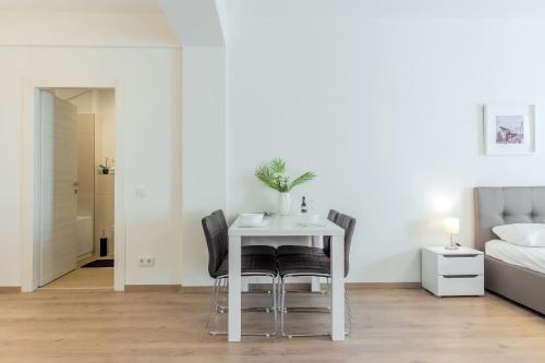 a white table and chairs in a room with a bed at ATLAS UNIRII: Upscale Flats in the Heart of Bucharest! in Bucharest