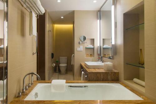 a bathroom with a tub and a toilet and a sink at Holiday Inn Nanyang by IHG in Nanyang