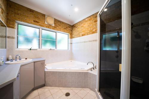 une salle de bain avec une baignoire, un lavabo et une douche dans l'établissement Beachfront Escape, à Forster