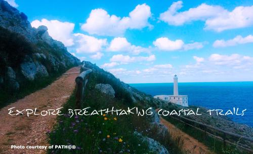 a dirt road next to the ocean with a lighthouse at B&B Villa Giuliana in Arnesano