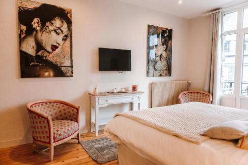 Un dormitorio con una cama y dos sillas y un televisor. en Chambre Roméo ou Juliette, en Honfleur