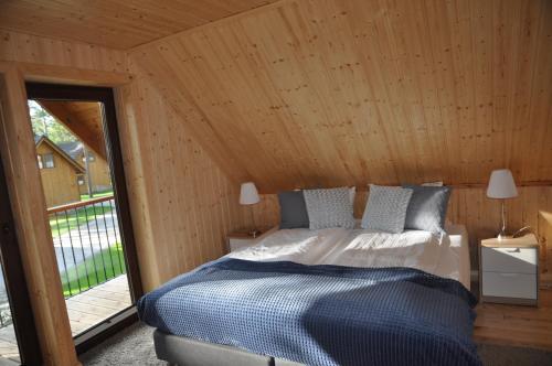 ein Schlafzimmer mit einem Bett in einem Holzzimmer in der Unterkunft Domki Largo nad Jeziorem Wdzydze in Borsk
