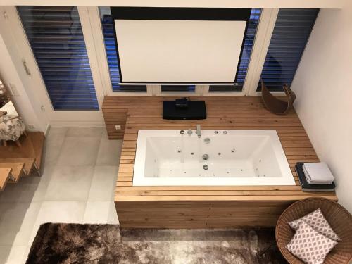 La salle de bains est pourvue d'une baignoire et d'un grand écran. dans l'établissement Terrassenpark Apartments (Premium Rooms), à Sasbachwalden
