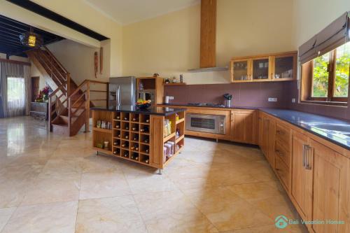 a large kitchen with wooden cabinets and a staircase at Villa Lumba Lumba - When perfection isn't enough! in Bubunan