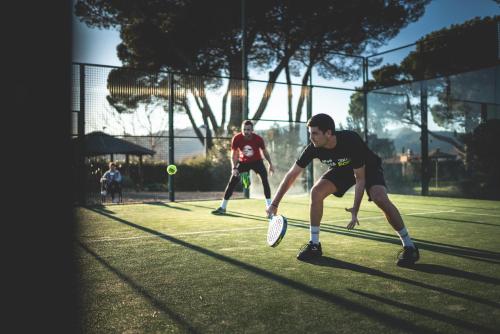 two men playing tennis on a tennis court at Hotel Mas Solà in Santa Coloma de Farners