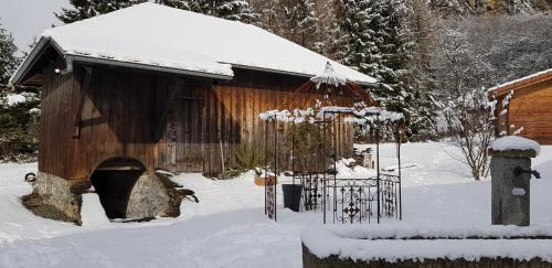a woodenshed with snow on it in a yard at Le Relais Du Mont Blanc in Magland