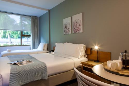 Cette chambre comprend deux lits, une table et une fenêtre. dans l'établissement Kings Park Motel, à Perth