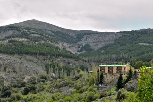 a building in a valley with mountains in the background at Hotel El Guerra in Güéjar-Sierra
