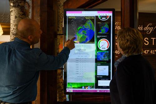 a man and a woman standing in front of a large screen at Fjellkysten in Tennevoll