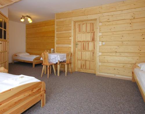 a bedroom with wooden walls and a table and chairs at Ośrodek Wczasowy Groń Placówka in Groń