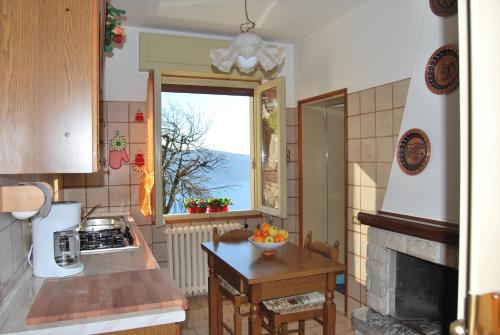 uma cozinha com uma janela e uma mesa com uma taça de fruta em Villa Margherita - Rebomaholidays em Tignale