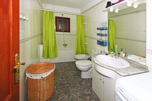 a bathroom with a sink and a toilet and green curtains at Casa Lorenzo in Tijarafe