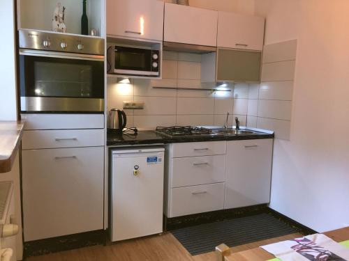 uma cozinha com armários brancos e um forno com placa de fogão em Travel Apartment em Varsóvia