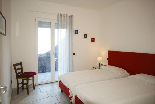 a bedroom with two beds and a chair and a window at Villa Ada - Theater Home in Tignale