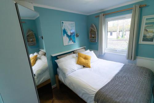 - une chambre avec des murs bleus et un lit avec des oreillers jaunes dans l'établissement Ocean Cottage, à Uny Lelant