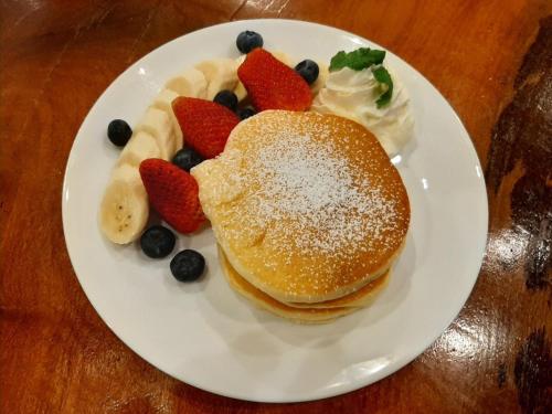 a white plate with pancakes and fruit on a table at Namtok Sarika Resotel in Nakhon Nayok