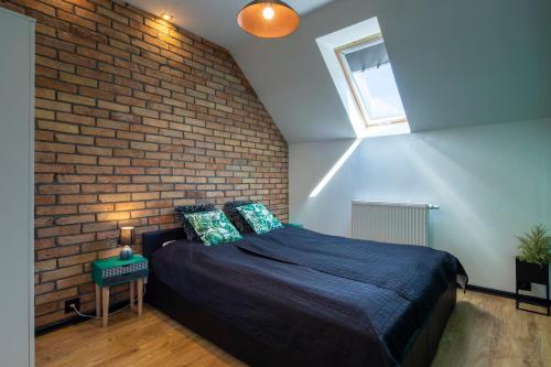 een slaapkamer met een bed en een bakstenen muur bij Apartament Zeglarski in Powidz