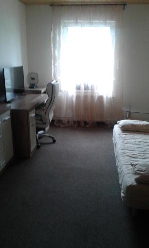 a room with a bed and a desk and a window at Hotel & Restaurant Adolfovský Dvůr in Adolfov