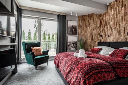 sypialnia z czerwonym łóżkiem i zielonym krzesłem w obiekcie Apartamenty Comfort & Spa Stara Polana VIPAPARTAMENTY w Zakopanem