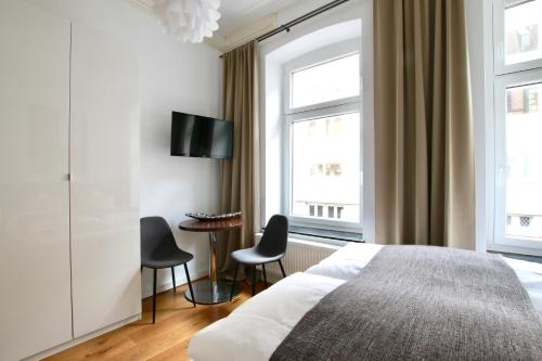 ケルンにあるArthouse Apartments am Eigelsteinのベッドルーム1室(ベッド1台、椅子2脚、テーブル付)