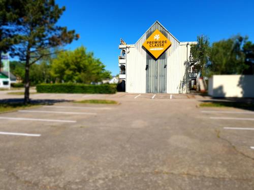 a parking lot with a caution sign in front of a building at Premiere Classe Nancy Est Essey in Essey-lès-Nancy