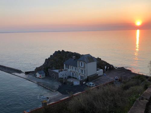 a house on an island in the water at sunset at Carpe Diem in Le Val-André