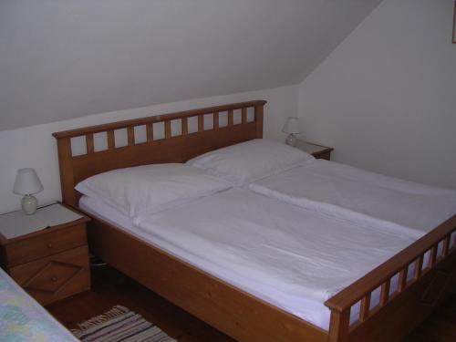 a bedroom with a bed with white sheets and two lamps at Neubauerhof in Liebenfels