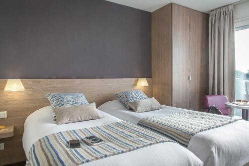 a hotel room with two beds and a window at Best Western Plus La Marina in Saint-Raphaël