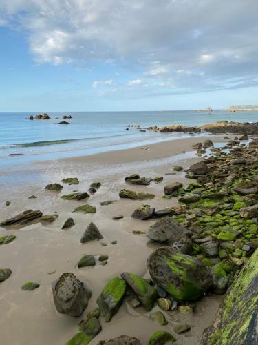 a beach with rocks and the ocean in the background at Hotel Rural Playa de Aguilar in Muros de Nalón