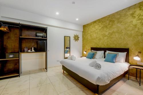 a bedroom with a large white bed with blue pillows at South Wind Guesthouse in Marsaxlokk