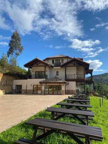 una fila de mesas de picnic frente a un edificio en Hotel Rural Playa de Aguilar en Muros de Nalón