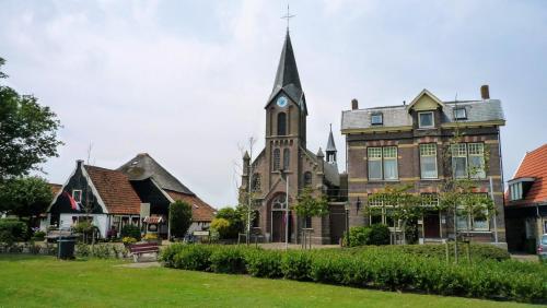 an old church with a clock tower in a yard at Pastorie Stella Marie in Oudeschild