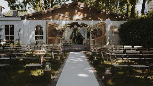 een buitenbruiloft met tafels en stoelen en een tent bij Parkhotel Hugo de Vries in Lunteren