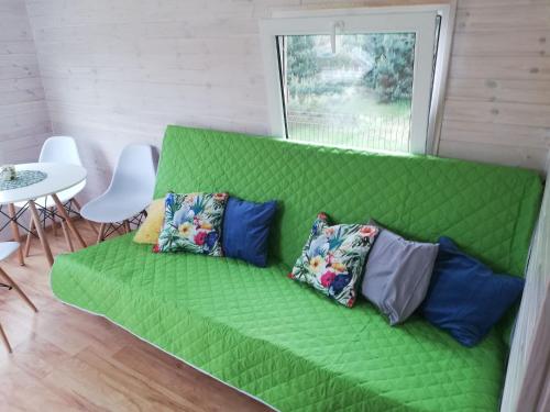 a green couch with pillows on it in a room at Miodowy Zakątek Całoroczne Domki i Pokoje przy Suntago, Deepspot, Pyszne Śniadania, Grill in Mszczonów
