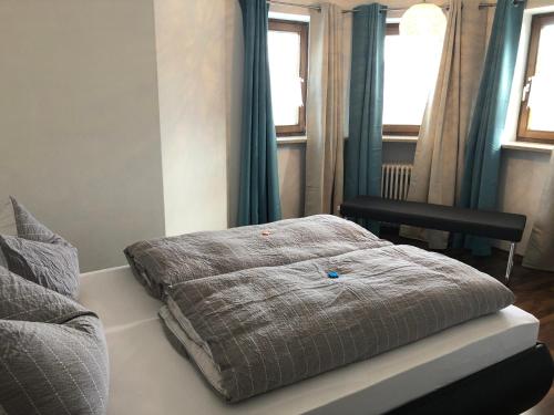 a bed sitting in a room with two windows at Gästehaus Aurikel 10 in Fischen