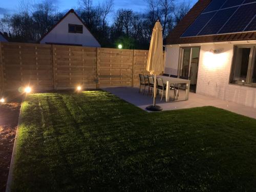 a lawn with a table and an umbrella in a yard at Duinendaele 166 met sauna en bij Plopsaland in De Panne