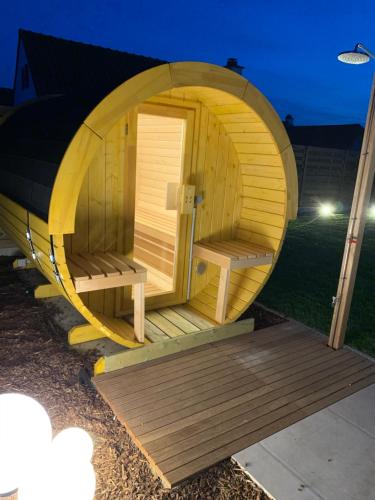 a round wooden sauna with a wooden deck at Duinendaele 166 met sauna en bij Plopsaland in De Panne