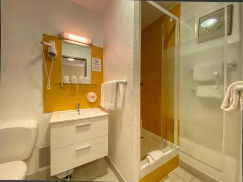 a bathroom with a toilet and a sink and a shower at Hôtel Le P'tit Monde in Montignac