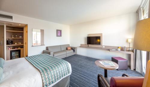 a hotel room with a bed and a couch at Best Western Plus La Marina in Saint-Raphaël