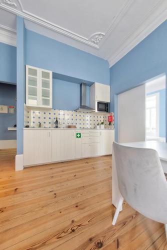 a kitchen with blue walls and a table and a chair at Aveiro History Apartments in Aveiro